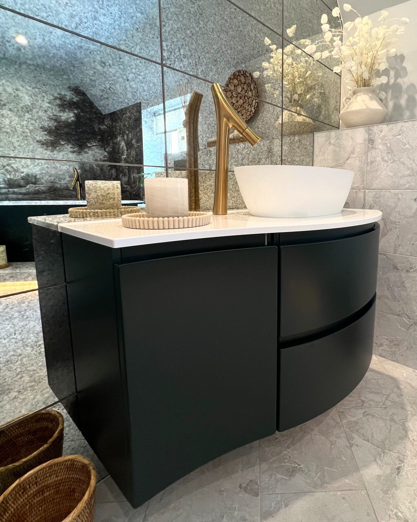 Curved dark vanity unit with a countertop basin and brass tap