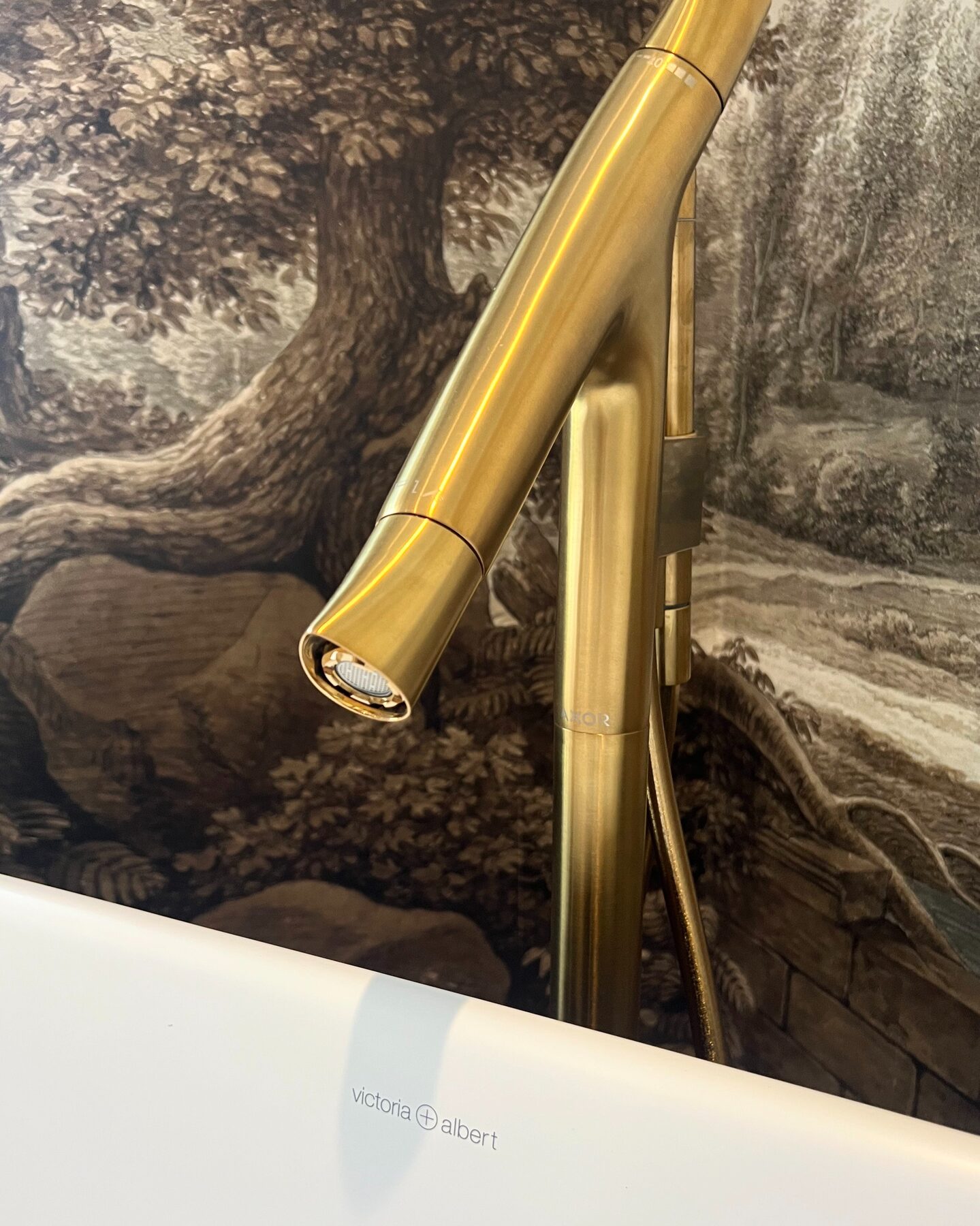 Brass freestanding bath tap against a landscape mural